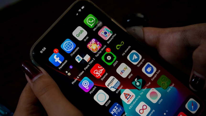 woman's hand with painted finger nails holds a phone with multiple apps