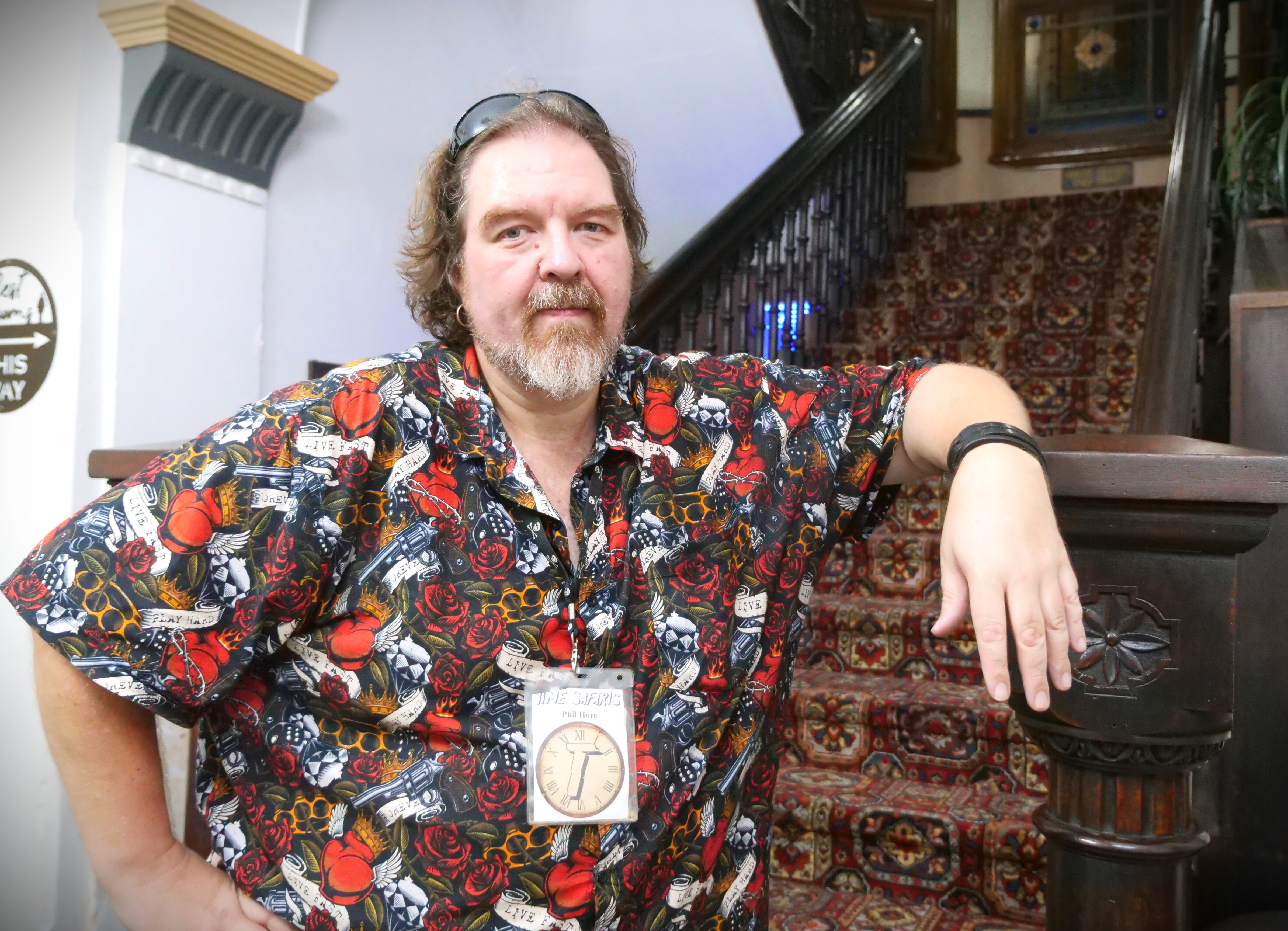 A man standing in front of a well-lit, grand staircase inside a pub