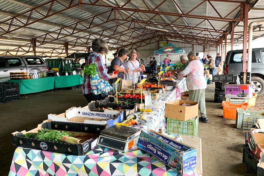 Shoppers with produce wait to be served at a market stall.