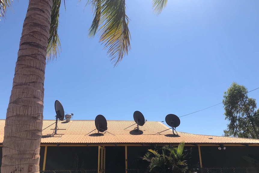 A house with four satellite dishes on the roof.