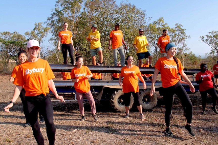 People in orange and red Skybury shirts dancing on the ground and on a trailer