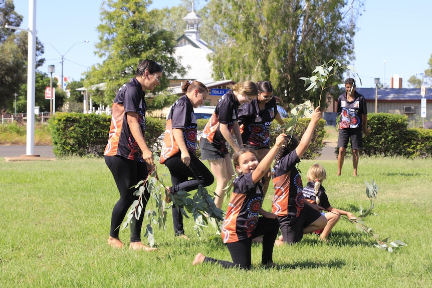 A group of young children dance with native flora