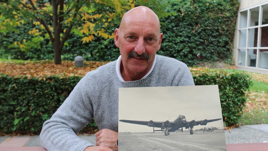 Fraser Simpson with a picture of the Lancaster aeroplane his father flew in WWII.