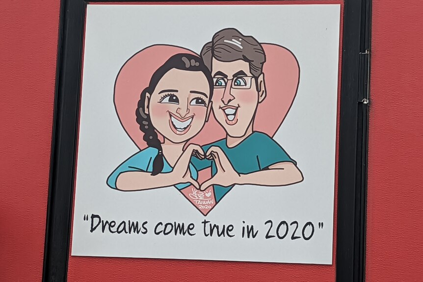 A caricature of a Taiwanese woman and a white man in a pink love heart on the side of a red food van.