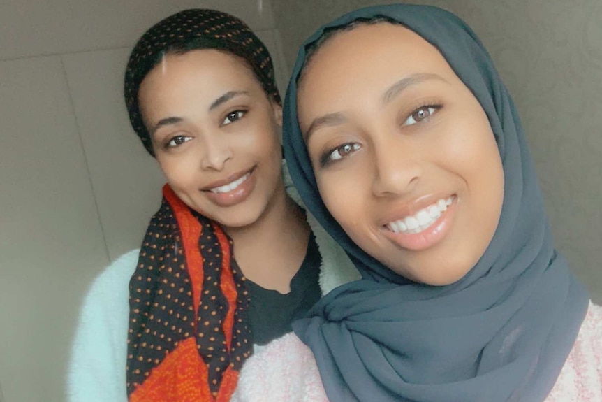 Two young women take a selfie in an apartment.