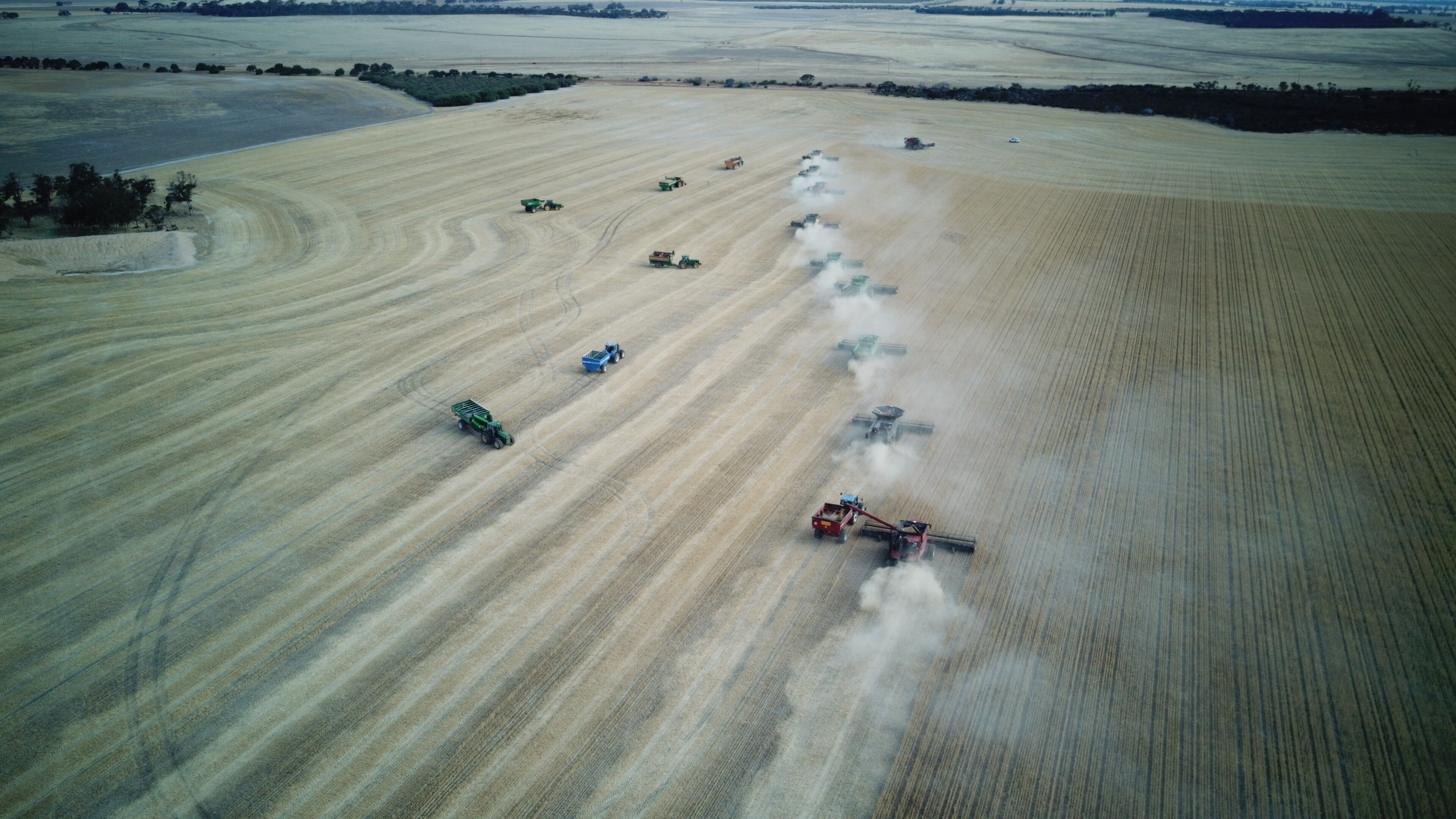 An aerial shot of harvesting machinery at work in a paddock.