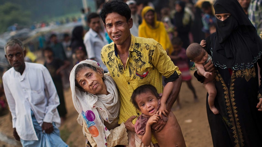 A man helps an elderly woman and a child along a path.