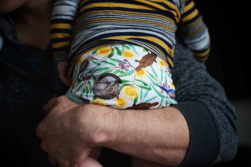 Close-up of Justin Ward holding one of his triplets.