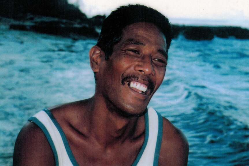 Archival close-up image of a smiling man by the ocean water in Banaba, Fiji.