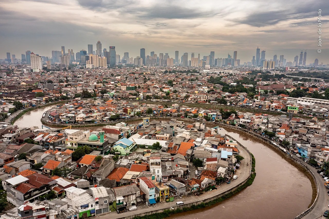 A bird's eye view of a brown river winding through a city