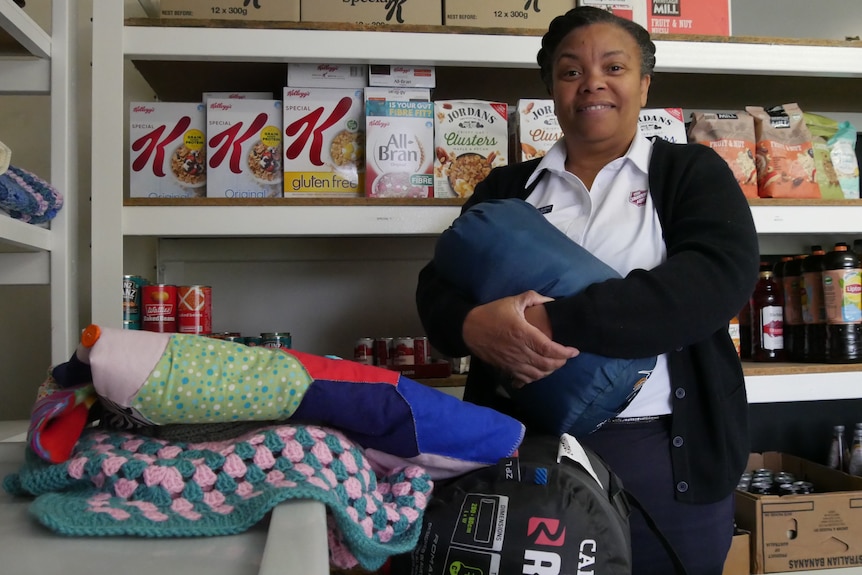 woman holding a sleeping bag in front of a food pantry