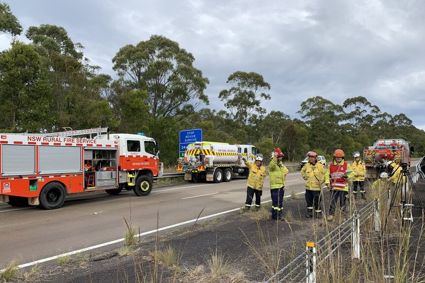 Fire crews stand on side of the Pacific Highway