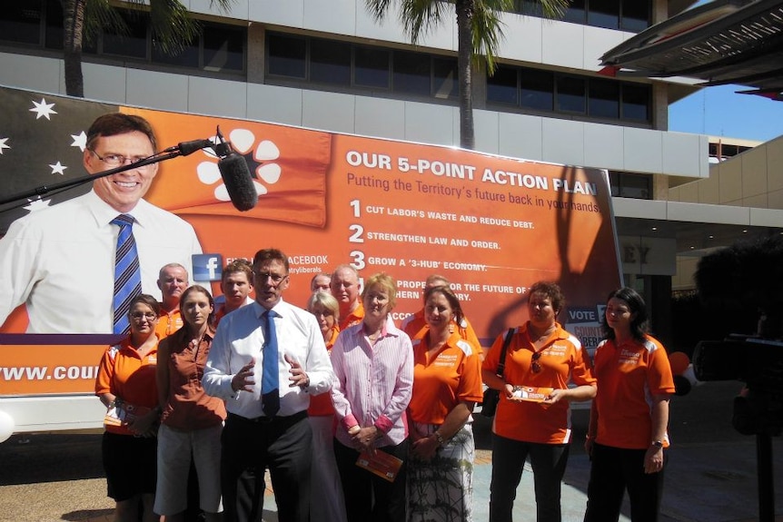 A group of Country Liberals people stand with Kezia Purick and Terry Mills in front of a large party poster