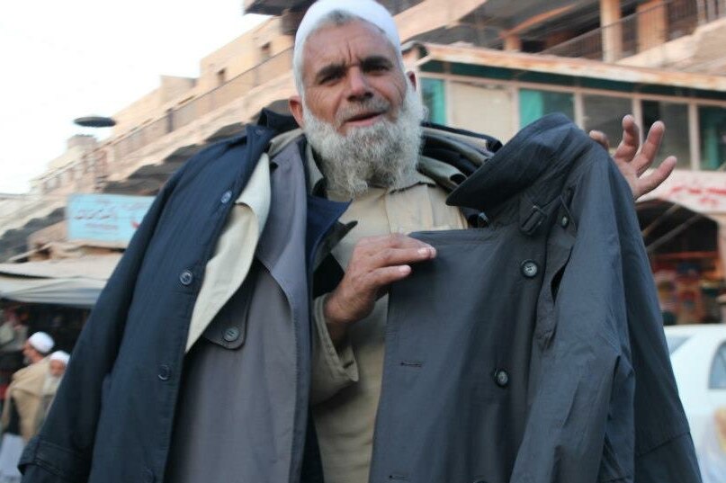 An Afghan street merchant holds up a jacket.