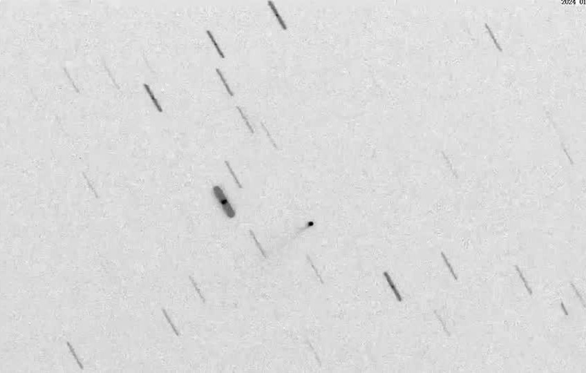 A screenshot from a satellite video showing a small dot amid streaks of passing debris