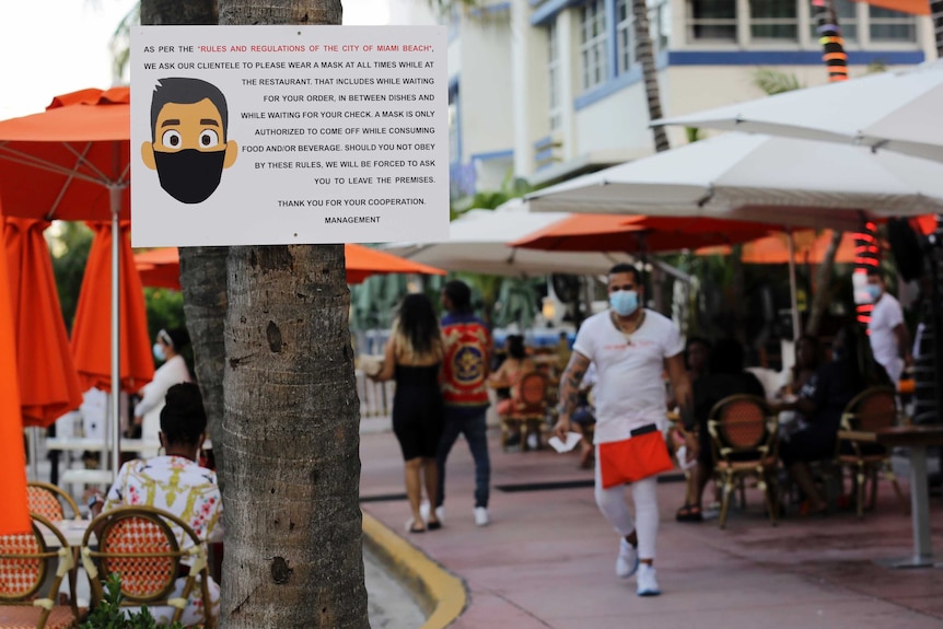 A sign informs customers at the Edison Hotel restaurant about wearing a protective face mask during the coronavirus pandemic