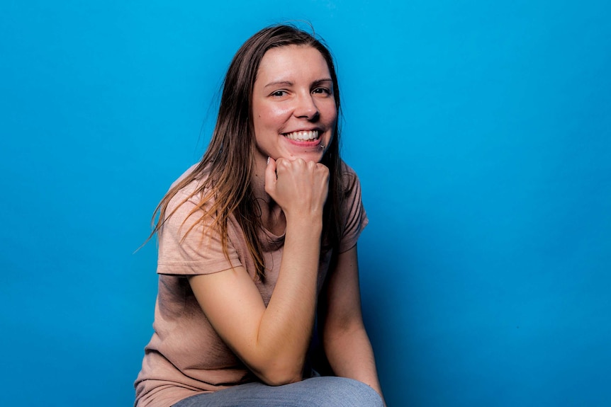 A portrait of a smiling woman against a blue background.