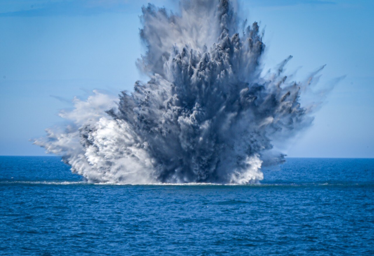 A large cloud of smoke rising from a large body of water.
