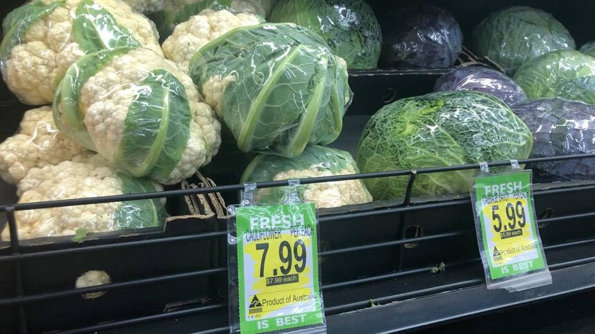 A supermarket shelf displaying cauliflowers marked with a $7.99-per-unit pricetag.
