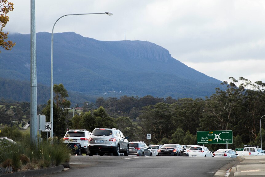 Traffic queueing at a roundabout with kunanyi/Mount Wellington in the background.