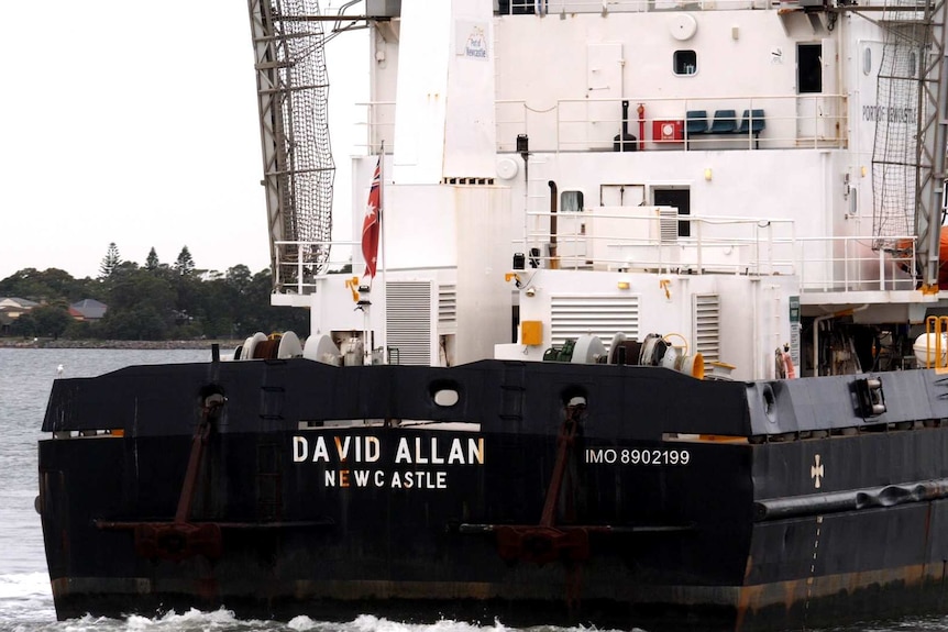 A black and white dredge called the David Allan viewed from behind.