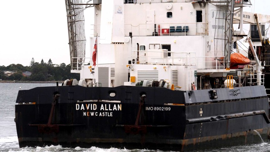 A black and white dredge called the David Allan viewed from behind.
