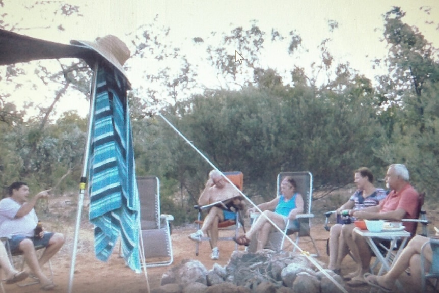 Group of baby boomers sitting around fire in outback