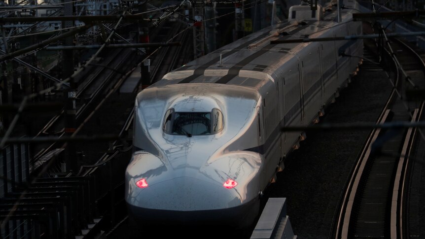 A Shinkansen bullet train on a track in a city.