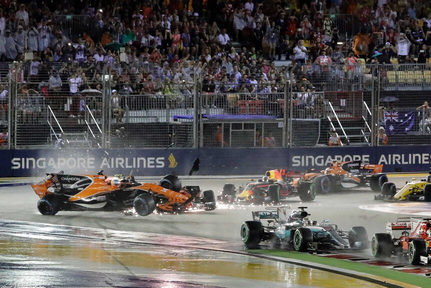 Fernando Alonso's car is seen rising up into the air amid sparks as it rounds a corner.