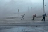 People run through sea spray in Wales