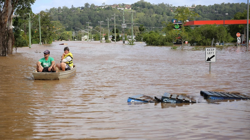 Floodwater in a Lismore street in 2017 with two people in a small boat.