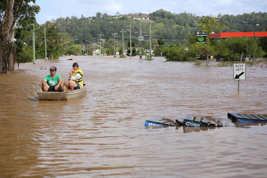 Floodwater in a Lismore street in 2017 with two people in a small boat.