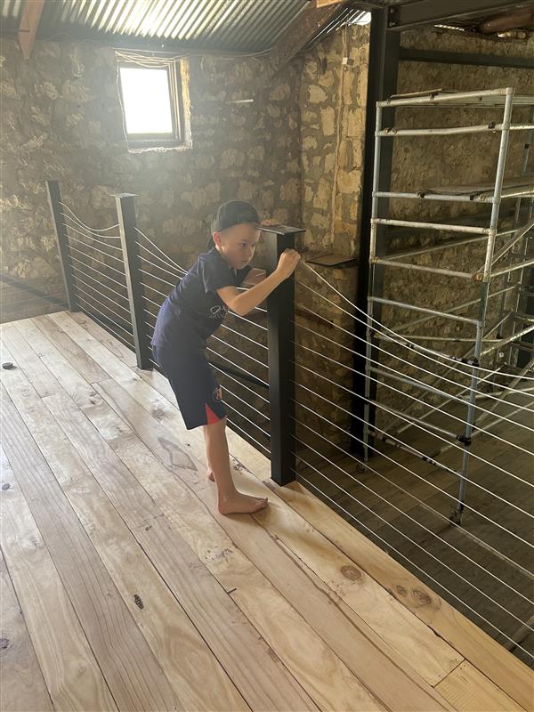 Un niño pequeño con sombrero se para junto a un poste y tira de unos cables.