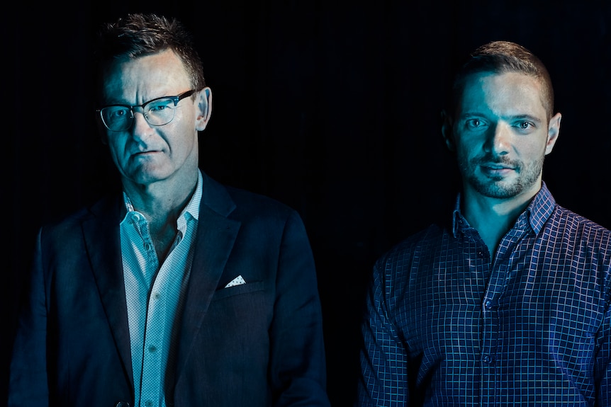 Two men in a darkened room with blue lighting