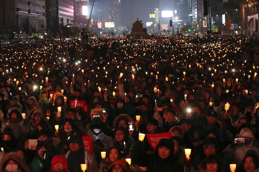 A massive crowd of people holding candles.