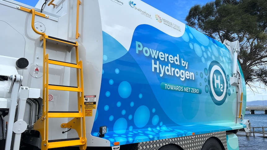 The exterior of the blue and white hydrogen-powered garbage truck and yellow ladder up the side.