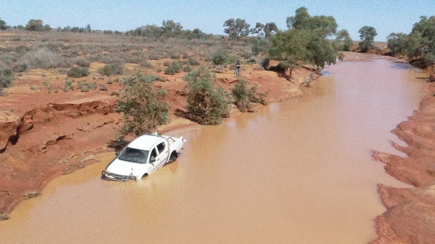 4WD submerged in deep floodwaters by outback dirt road