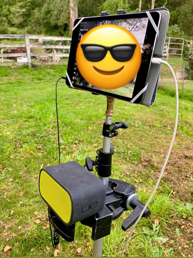 iPad on stand with smiling face emoji on screen.