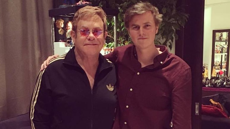 Sir Elton John and Tate Sheridan stand with their arms around each other
