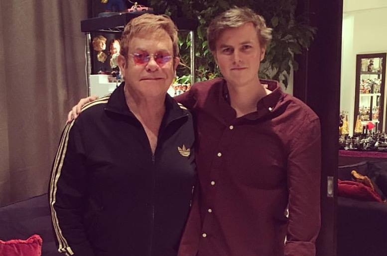 Sir Elton John and Tate Sheridan stand with their arms around each other