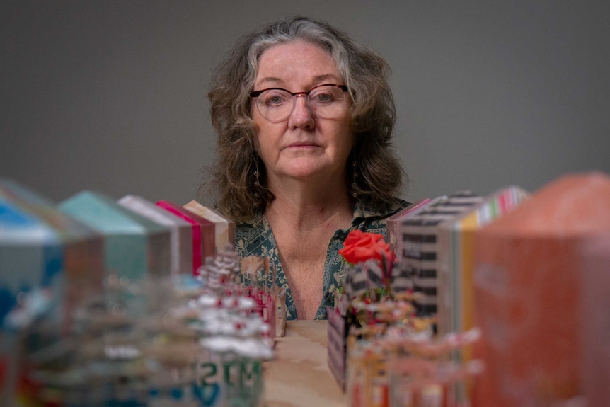 Portrait of an older woman between between paper memorials made from scrapbooking paper.