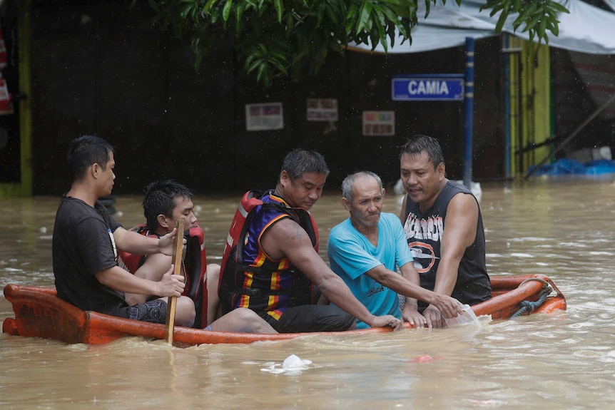 Residents ride a boat as they evacuate from their flooded homes
