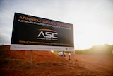 A large sign reading 'Arnhem Space Centre', on a patch of red dirt.