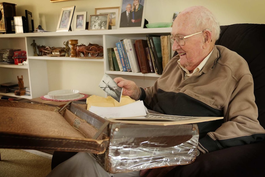 Stan McKay sits on a chair, sorting through a box filled with old keepsakes