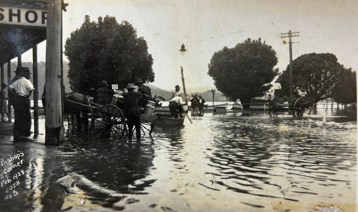 Fotografia em preto e branco de 1928 de pessoas do lado de fora de uma loja durante uma enchente.