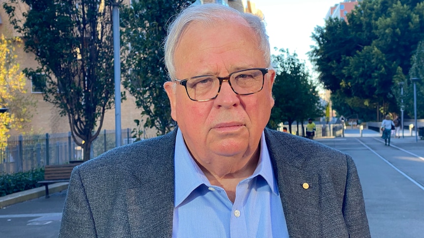 an elderly man wearing glassed looking forward