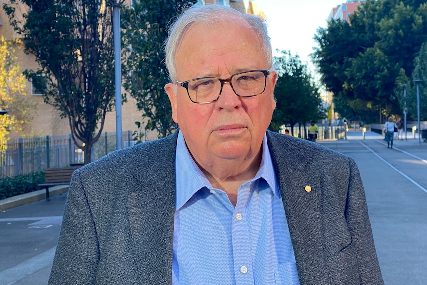 an elderly man wearing glassed looking forward