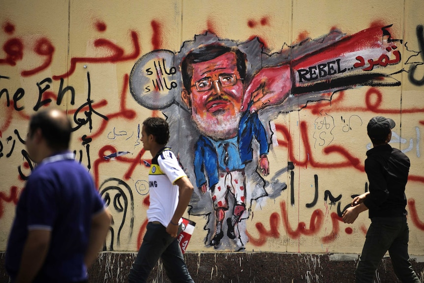 Egyptians walk past anti-Morsi graffiti