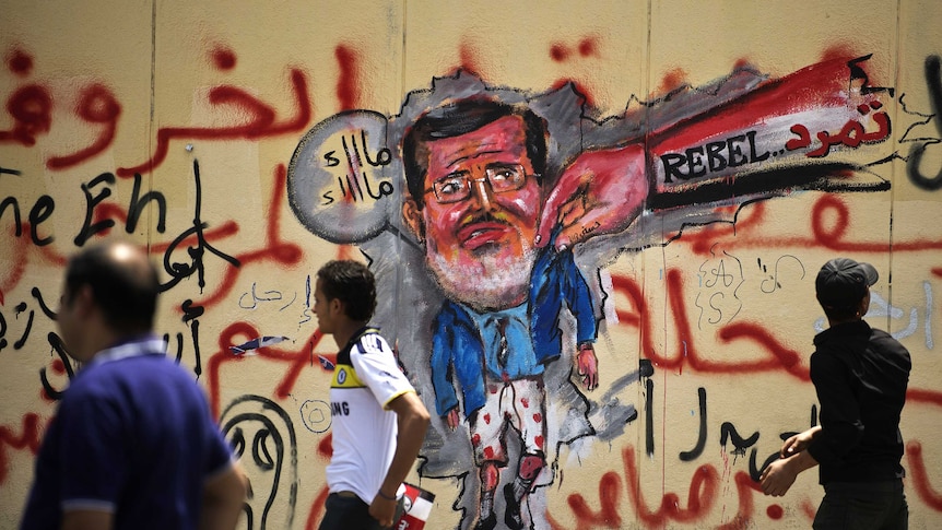 Egyptians walk past anti-Morsi graffiti