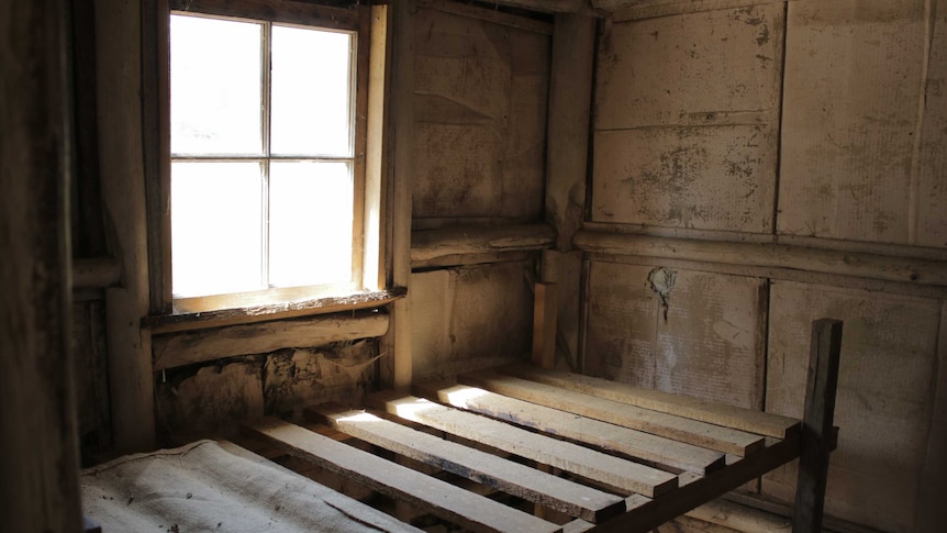 A decrepit room flooded with light from a square window.